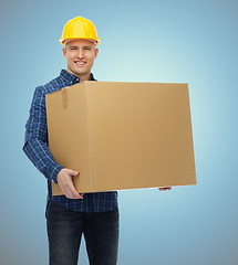 Image showing smiling male builder in helmet with cardboard box