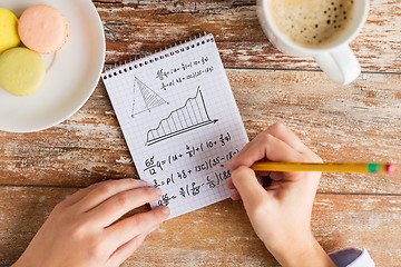 Image showing close up of hands writing mathematical equation