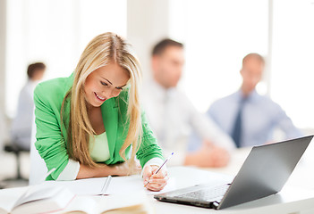 Image showing attractive businesswoman taking notes in office