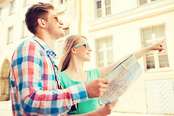 Image showing smiling couple with map and photo camera in city