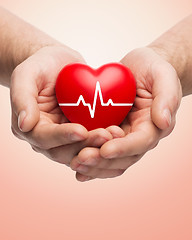 Image showing close up of hands holding heart with cardiogram