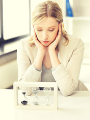 Image showing pensive businesswoman with sand glass