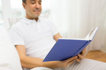 Image showing close up of happy man reading book at home