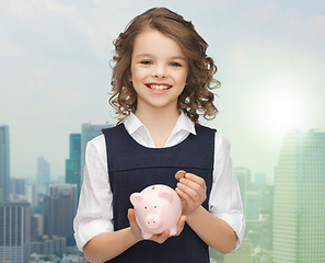 Image showing happy girl holding piggy bank and coin