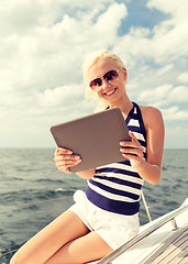 Image showing smiling woman sitting on yacht with tablet pc