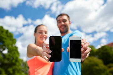 Image showing two smiling people with smartphones outdoors