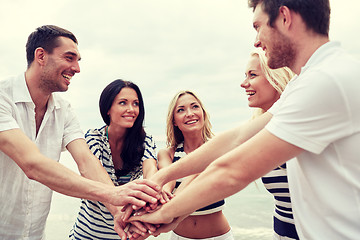 Image showing smiling friends putting hands on top of each other