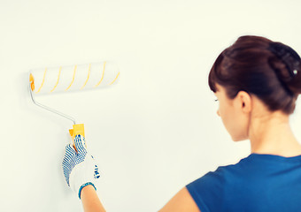 Image showing woman with roller and paint colouring the wall