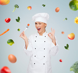 Image showing smiling female chef with fork and tomato