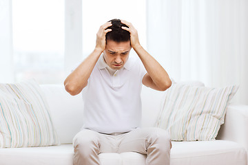 Image showing unhappy man suffering from head ache at home