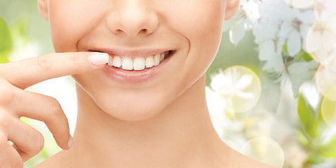 Image showing close up of smiling woman face pointing to teeth