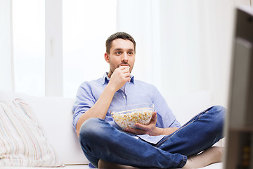 Image showing young man watching tv and eating popcorn at home