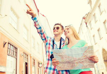 Image showing smiling couple with map and photo camera in city