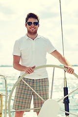 Image showing young man in sunglasses steering wheel on yacht