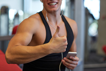 Image showing happy man with smartphone and earphones in gym