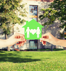 Image showing hands holding green house with family