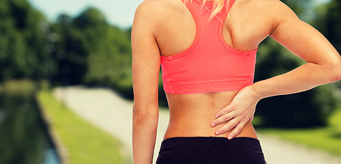 Image showing close up of sporty woman touching her back