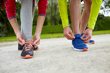 Image showing close up of couple tying shoelaces outdoors