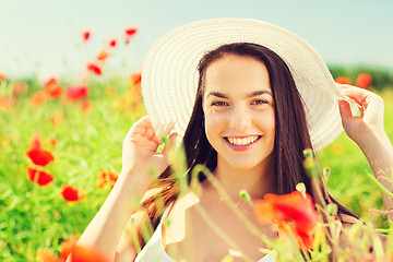 Image showing smiling young woman in straw hat on poppy field