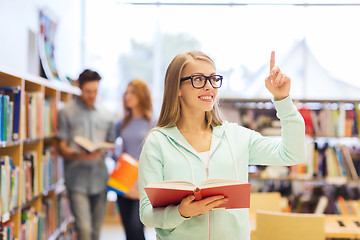 Image showing happy student girl or woman with book in library