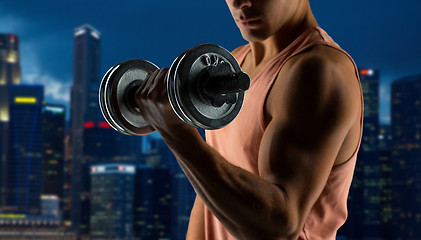 Image showing close up of young man with dumbbell flexing biceps