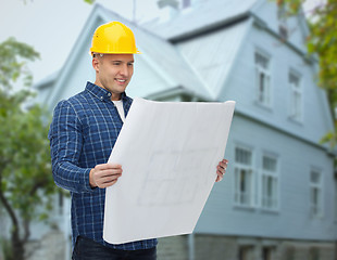 Image showing smiling builder with blueprint over house