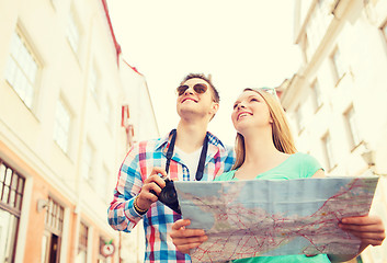 Image showing smiling couple with map and photo camera in city