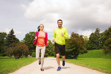 Image showing smiling couple with earphones running outdoors