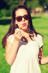 Image showing smiling young girl with soap bubbles in park