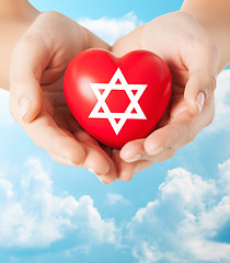 Image showing close up of hands holding heart with jewish star