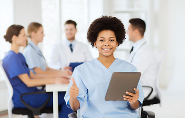 Image showing happy doctor with tablet pc over team at clinic
