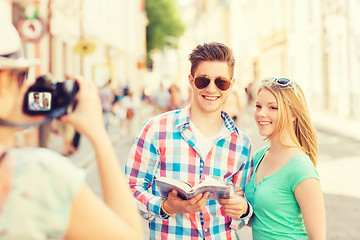 Image showing smiling couple with map and photo camera in city