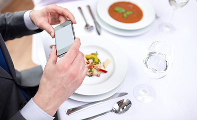 Image showing close up of couple with smartphones at restaurant