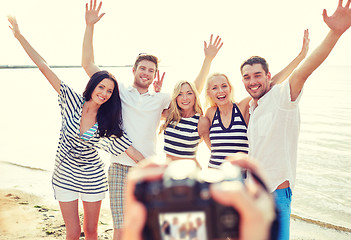 Image showing friends on beach waving hands and photographing