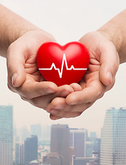 Image showing close up of hands holding heart with cardiogram