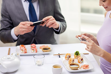 Image showing close up of couple with smartphones at restaurant