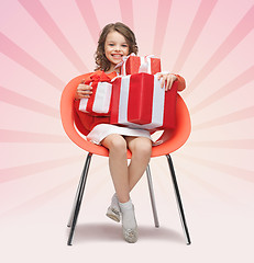 Image showing happy little girl with gift boxes sitting on chair