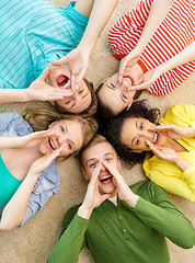 Image showing smiling people lying down on floor and screaming