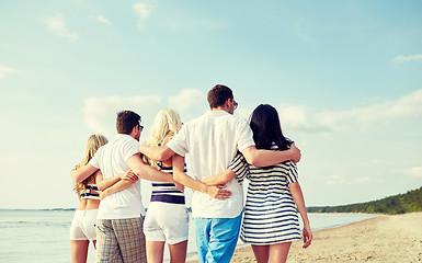 Image showing smiling friends hugging and walking on beach