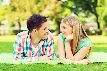 Image showing smiling couple lying on blanket in park