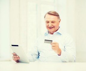 Image showing old man with tablet pc and credit card at home