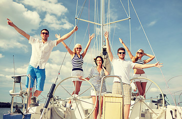 Image showing smiling friends sitting on yacht deck and greeting