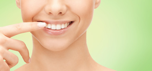 Image showing close up of smiling woman face pointing to teeth