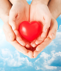 Image showing close up of couple hands holding red heart