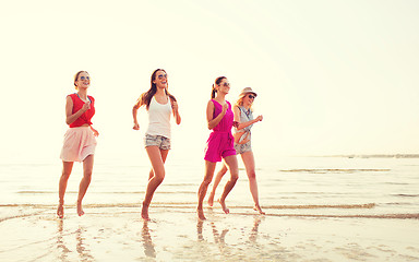 Image showing group of smiling women running on beach