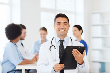 Image showing happy doctor with clipboard over medical team