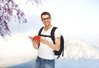 Image showing happy young man with backpack and book travelling