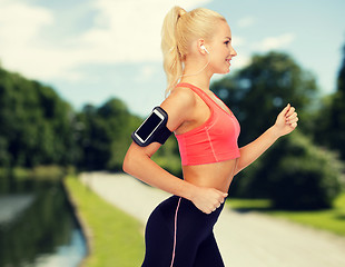 Image showing sporty woman running with smartphone and earphones