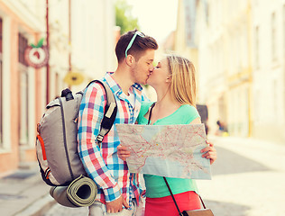 Image showing smiling couple with map and backpack in city