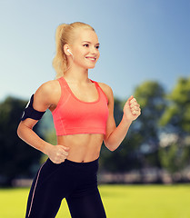 Image showing sporty woman running with smartphone and earphones